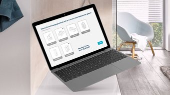 Ein Laptop schwebt über einem Badezimmerwaschtisch, während eine Auswahl an Badezimmermöbeln auf dem Bildschirm angezeigt wird.