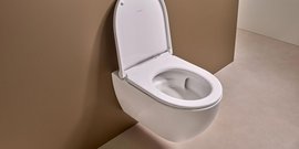 Eine moderne, wandmontierte Toilette mit einem eleganten, weißen Design vor einer braunen Wand.