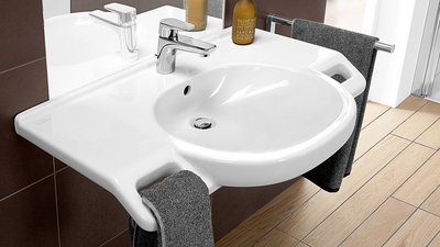 Ein modernes Waschbecken mit einem eleganten Wasserhahn und einem Handtuchhalter, umgeben von stilvollen Fliesen.