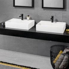 Ein modernes Badezimmer mit zwei weißen Waschbecken auf einer schwarzen Ablage, umgeben von eleganten Spiegeln.